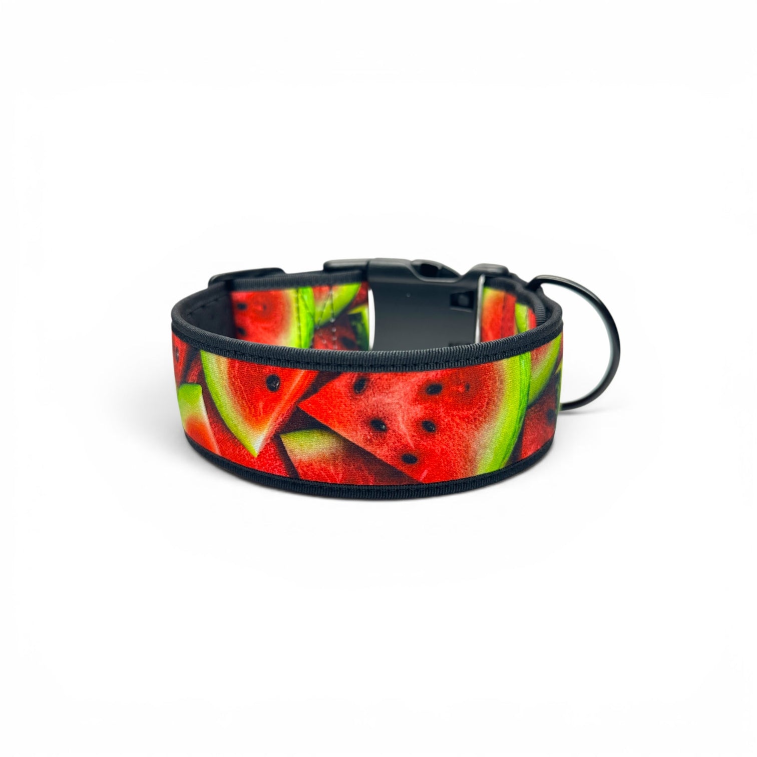 A dog collar featuring a vibrant watermelon slice pattern with red, green, and black details, complete with a black plastic buckle and a black metal ring, shown on a plain white background.