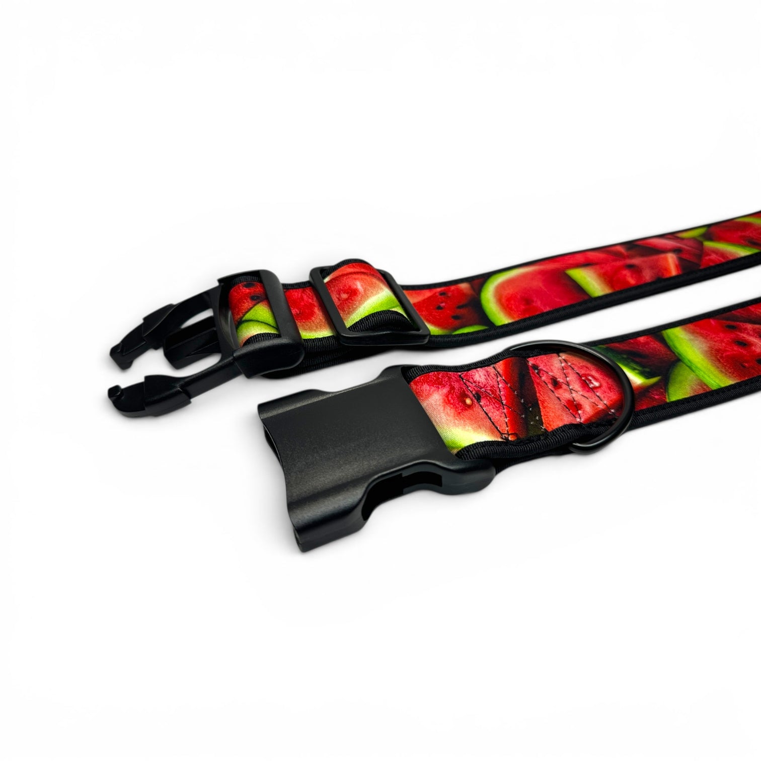A close-up of a dog collar strap featuring a vibrant watermelon slice pattern with red, green, and black details, secured with a black plastic quick-release buckle on a white background.